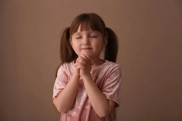 Religiosa chica cristiana rezando sobre fondo marrón — Foto de Stock