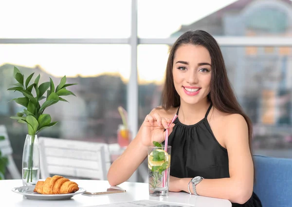 Молодая женщина со стаканом лимонада в кафе — стоковое фото