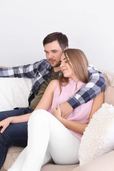 Niedliche junge schöne Paar sitzt auf dem Sofa zu Hause — Stockfoto