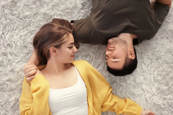 Mignon jeune beau couple couché sur le tapis à la maison — Photo