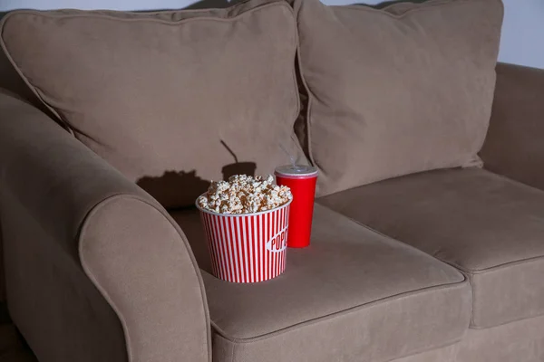 Leckeres Popcorn und Getränk auf der Couch, Nahaufnahme. Heimkino — Stockfoto