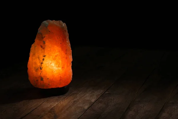 Гималайская соляная лампа на столе на тёмном фоне — стоковое фото