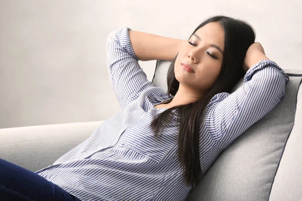 Молода жінка розслабляється на затишному дивані в світлій кімнаті — стокове фото