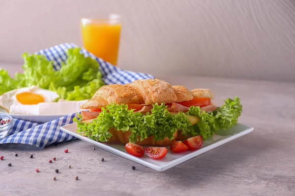 Plate with tasty croissant sandwich on table — Stock Photo, Image