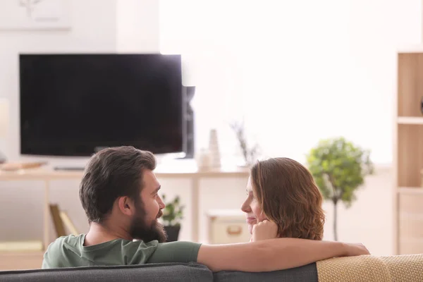 快乐的情侣坐在沙发上看电视在家里 — 图库照片