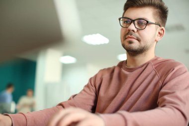 Genç adam ofiste çalışıyor.