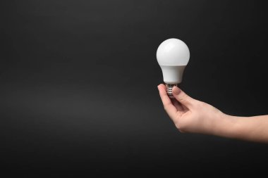 LED Lamba koyu arka plan üzerinde tutan kadın