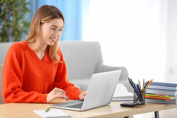 Estudante bonito com laptop estudando na mesa dentro de casa — Fotografia de Stock