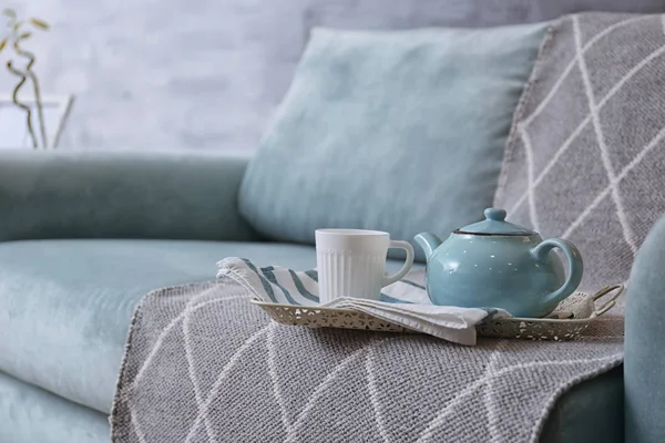 Tablett mit Teekanne und Tasse auf bequemem Sofa im Zimmer — Stockfoto