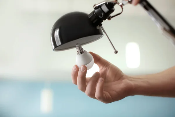 Man changing light bulb in lamp at home