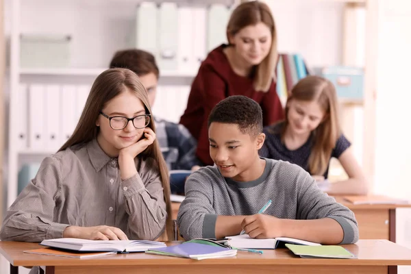 Groep tieners huiswerk met leraar in de klas — Stockfoto