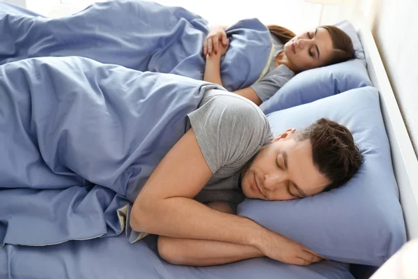 Νεαρό ζευγάρι στον ύπνο στο κρεβάτι στο σπίτι. Οικογένεια κατάκλιση — Φωτογραφία Αρχείου