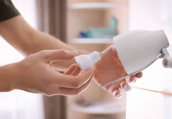 Man changing light bulb in lamp at home