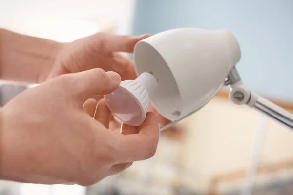 Man changing light bulb in lamp at home