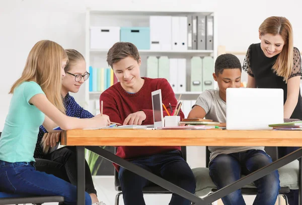 Gruppe af teenagere laver lektier med lærer i klasseværelset - Stock-foto