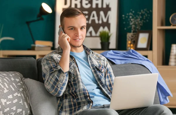 Ung man pratar telefonen medan du arbetar inomhus — Stockfoto