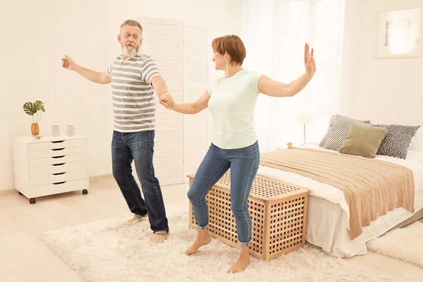 Happy mature couple dancing at home