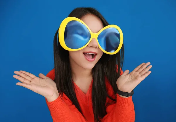 Young woman in funny disguise posing on color background. April fool's day celebration — Stock Photo, Image