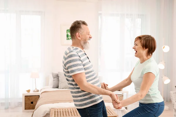 Happy mature couple dancing at home