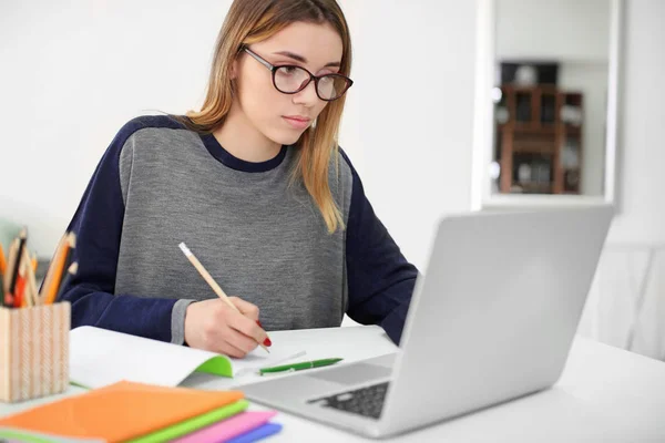 Mooie student met laptop studeren aan tafel binnenshuis — Stockfoto