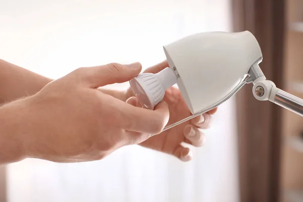 Man changing light bulb in lamp at home — Stock Photo, Image