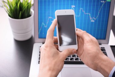 Hisse senedi grafiği veri üstünde perde ile Smartphone yakınındaki dizüstü bilgisayar kullanan adam. Forex kavramı