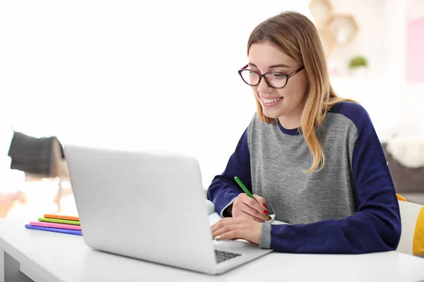 Estudante bonito com laptop estudando na mesa dentro de casa — Fotografia de Stock