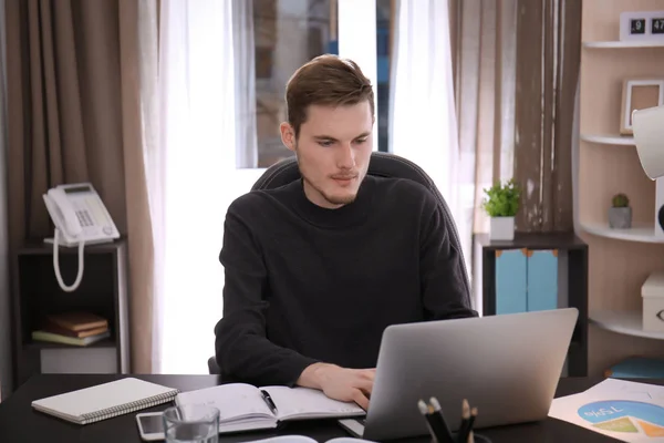 Młody mężczyzna pracujący z laptopa w pomieszczeniu — Zdjęcie stockowe