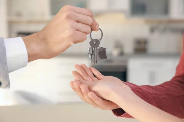 Агент з нерухомості дає ключ від будинку молодої пари в приміщенні — стокове фото