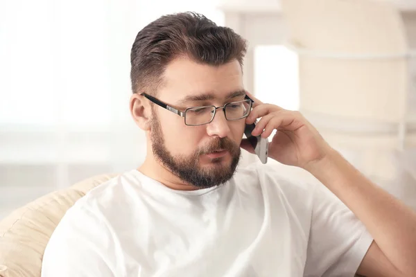 Jovem falando ao telefone enquanto trabalhava em casa — Fotografia de Stock