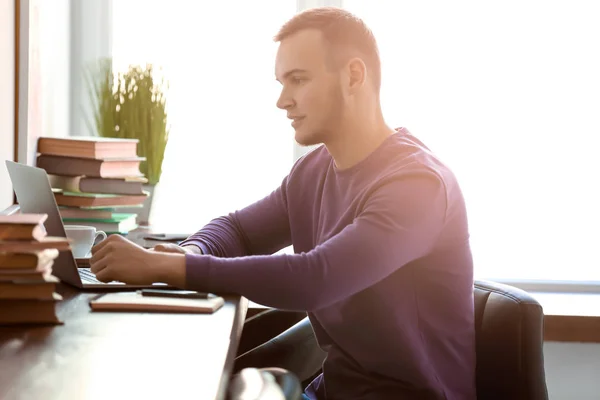 Hombre guapo trabajando con el ordenador portátil en el interior — Foto de Stock