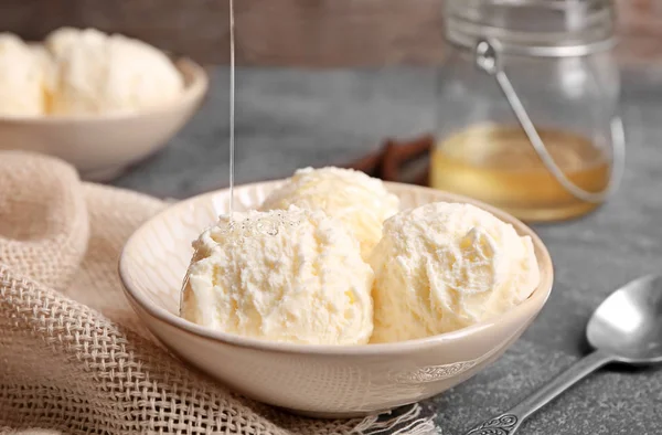 Despejar mel em delicioso sorvete de baunilha na tigela na mesa — Fotografia de Stock