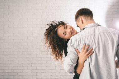 Genç çift hafif tuğla duvara sarılma sevgi dolu