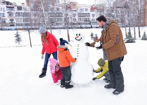 Glückliche Familie macht Schneemann im Park im Winterurlaub — Stockfoto