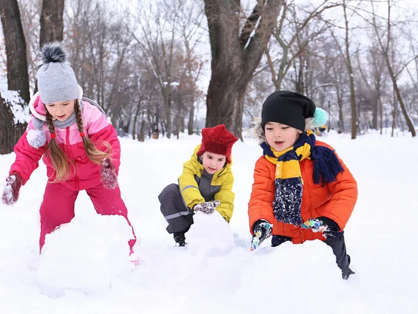 幸せな子供の冬休みに公園で雪だるまを作る — ストック写真