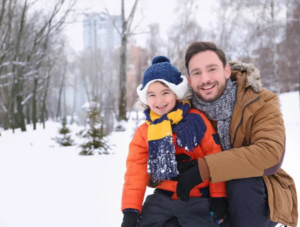 Šťastný muž se synem v zasněženém parku na zimní dovolenou — Stock fotografie