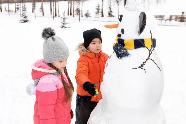 Happy children making snowman in park on winter vacation — Stock Photo, Image