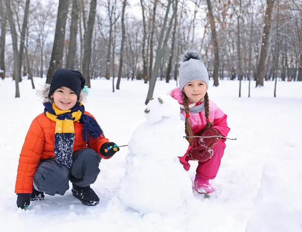 Szczęśliwe dzieci Dokonywanie bałwana w parku na ferie zimowe — Zdjęcie stockowe