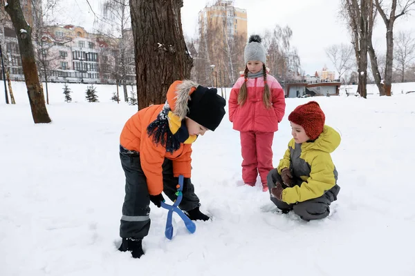 Dzieci bawiące się w parku snowy na ferie zimowe — Zdjęcie stockowe