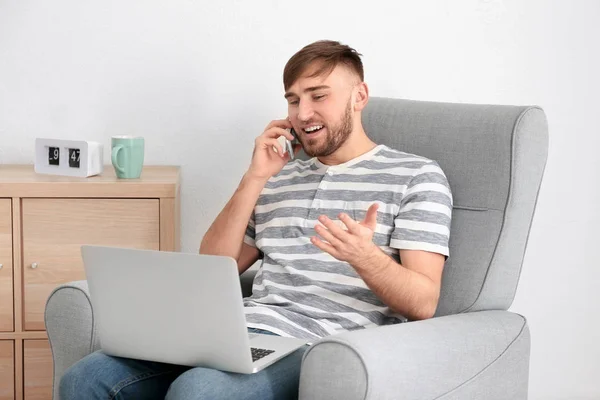 Young Man Talking Mobile Phone While Working Laptop Home — Stock Photo, Image