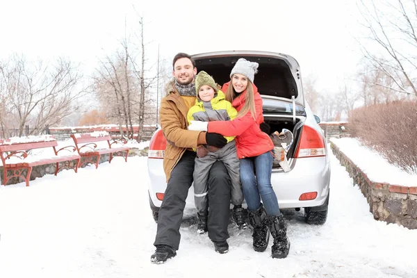 Happy family sitting in car trunk on winter vacation