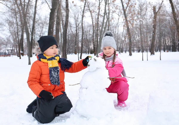 Glückliche Kinder basteln Schneemann im Park in den Winterferien — Stockfoto