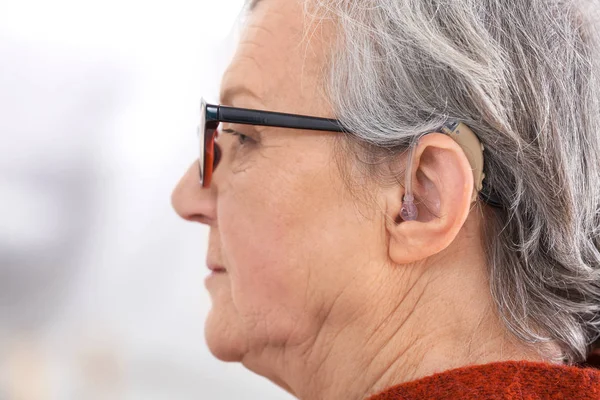 Зрелая женщина со слуховым аппаратом в помещении — стоковое фото