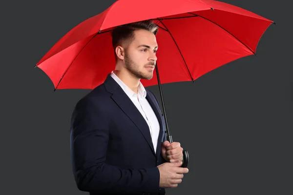 Joven en traje elegante con paraguas rojo — Foto de Stock