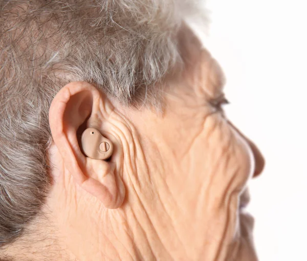 Старшая женщина со слуховым аппаратом на белом фоне — стоковое фото