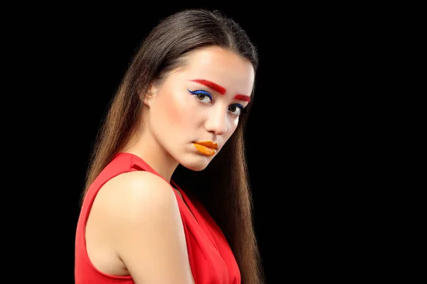 Ung kvinde med farvede øjenbryn og kreativ makeup på sort baggrund - Stock-foto