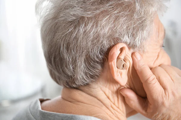 Seniorin mit Hörgerät drinnen — Stockfoto