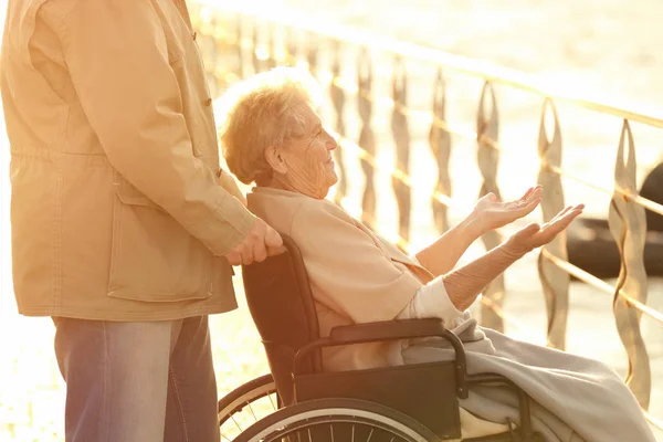 Senior kobieta na wózku inwalidzkim z przyjaciółką z domu w pobliżu rzeki opieki — Zdjęcie stockowe