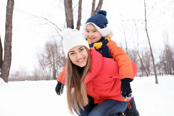 Ευτυχισμένη γυναίκα με γιο στο χιονισμένο πάρκο στις χειμερινές διακοπές — Φωτογραφία Αρχείου