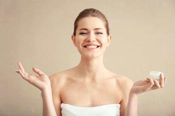 Junge Frau mit einem Glas Handcreme auf farbigem Hintergrund — Stockfoto